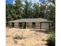 New construction home with neutral paint, dark trim, and attached one-car garage in a wooded setting at 20769 Sw Oriole Dr, Dunnellon, FL 34431