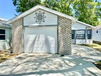 Single Gathering home shows a one car garage, brick trim, and well-lit driveway, with an ornamental design on the upper portion at 2305 Ne 40Th Ave, Ocala, FL 34470