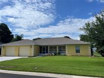 Charming yellow home with a two-car garage and well-maintained lawn under a blue sky at 4622 Ne 15Th St, Ocala, FL 34470