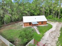 Charming log cabin with metal roof, green lawn, and perimeter fence offers rustic appeal and modern convenience at 5630 Se 183Rd Avenue Rd, Ocklawaha, FL 32179