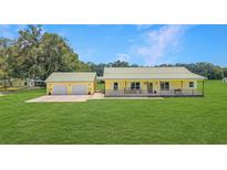 Charming yellow ranch home with a metal roof, a covered porch and an oversized two-car garage at 975 Cr 542E, Bushnell, FL 33513