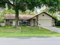 Charming single-story home featuring a stone accent, attached garage, and a well-manicured front lawn at 1112 Ne 130Th Ter, Silver Springs, FL 34488