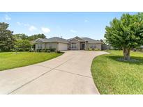 Charming single story home with a large driveway and well-manicured lawn and mature landscaping at 2413 Se 23Rd St, Ocala, FL 34471