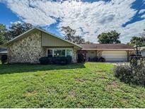 Charming stone-accented home featuring a well-maintained lawn, red front door and attached two-car garage at 3545 Se 24Th Ave, Ocala, FL 34471