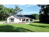 Charming single-story home with stone accents, gray roof and lush green lawn and manicured landscaping at 7 Hill Prince Dr, Ocala, FL 34482