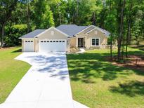 Inviting single-story home featuring a spacious driveway, three-car garage, and a beautifully landscaped front yard at 7695 Sw 188Th Ave, Dunnellon, FL 34432