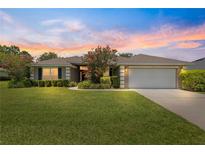 Inviting home with lush lawn, mature landscaping, and attached two car garage at 8 Diamond Club Rd, Ocala, FL 34472