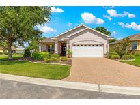 Charming single-story home featuring a paver driveway, lush landscaping, and a well-maintained lawn at 8566 Sw 83Rd Loop, Ocala, FL 34481