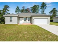 Inviting single-story home with a well-manicured lawn, a two-car garage, and neutral-colored exterior at 15212 Sw 27Th Ct, Ocala, FL 34473