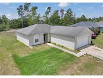 Exterior view of a charming single story home with a well-manicured lawn and an attached two-car garage at 15711 Sw 52Nd Avenue Rd, Ocala, FL 34473