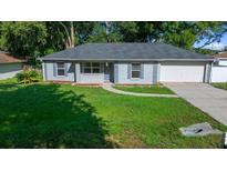 Charming single-story home with a well-manicured lawn, blue shutters, and an attached garage at 26 Hemlock Terrace Dr, Ocala, FL 34472