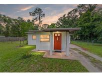 Charming single-story home featuring a red door, stucco siding, and a well-maintained front lawn at 2602 Ne 2Nd Ave, Ocala, FL 34470