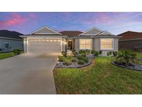 Charming single-story home featuring a well-manicured lawn, lovely landscaping, and an attached two-car garage at 4416 Homan Loop, The Villages, FL 32163