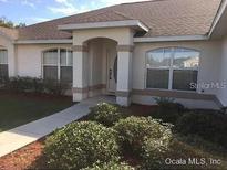 Inviting home featuring a well-manicured lawn and a charming entryway with lush landscaping at 4420 Sw 100Th St, Ocala, FL 34476