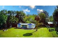 Charming cottage-style home with blue trim, lush lawn, and mature trees in a serene setting at 626 Ne 21St St, Ocala, FL 34470
