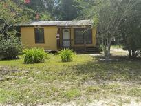 Charming yellow home with a cozy porch and mature landscaping at 6415 Ne 23Rd Ave, Ocala, FL 34479