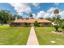 Charming brick home featuring lush lawn, mature trees, and a welcoming walkway to a double door entry at 3555 Sw 24Th Avenue Rd, Ocala, FL 34471