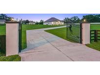 Elegant gated entrance with long drive leading to a well-manicured lawn and stunning modern farmhouse at 7041 Ne 22Nd Court Rd, Ocala, FL 34479