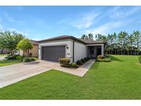 Charming single-story home featuring a well-manicured lawn, gray garage door, and inviting front entrance at 7707 Sw 94Th Cir, Ocala, FL 34481