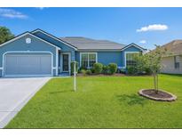 Charming single story home featuring a well-manicured front lawn, landscaped garden beds, and a two-car garage at 8187 Sw 60Th Ter, Ocala, FL 34476