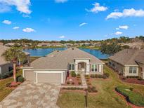 Charming single-story home boasts a beautiful lake view, mature landscaping, and a spacious three-car garage at 9415 Se 125Th St, Summerfield, FL 34491