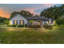 Charming single-story home featuring tidy landscaping, a covered porch, and elegant exterior lighting at 10600 Se 32Nd Ave, Ocala, FL 34480
