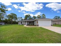 Charming single Gathering home featuring a well-manicured lawn, attached two-car garage, and welcoming front porch at 13479 Sw 100Th Ln, Dunnellon, FL 34432