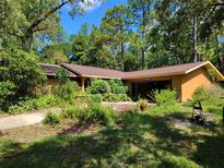 Inviting one-story home surrounded by lush greenery and trees under a bright blue sky at 20045 Sw 88Th Place Rd, Dunnellon, FL 34431