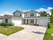 Beautiful two-story home with a two-car garage and a landscaped yard with green grass and blue skies at 7067 Sw 60Th Ln, Ocala, FL 34474
