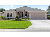 Charming one-story home features a well-manicured lawn, neutral stucco, and a two-car garage at 7243 Se 172Nd Legacy Ln, The Villages, FL 32162