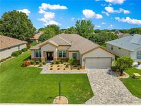 Beautiful single-story home with a manicured lawn, paver driveway, and attached two car garage at 9120 Se 125Th Loop, Summerfield, FL 34491