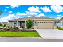 Charming single-story home featuring a manicured lawn, neutral tones, and an attached two-car garage at 10597 Sw 90Th Street Rd, Ocala, FL 34481