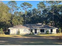 Charming single-story home featuring a neutral palette, well-maintained lawn, and lush surrounding trees at 1245 Nw 73Rd Ter, Ocala, FL 34482