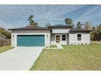 Charming single-story home featuring a modern design, blue garage door, and well-maintained lawn at 3325 Sw 165Th Loop, Ocala, FL 34473