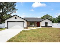 Charming single-story home featuring a two-car garage, landscaped front yard, and neutral color palette at 36 Pine Radl, Ocala, FL 34472