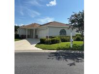 Charming single story home with well-manicured landscaping, a two-car garage, and a concrete driveway at 8689 Se 141St Street Rd, Summerfield, FL 34491