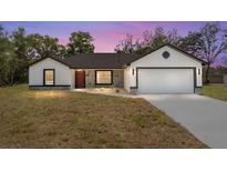 Charming single-story home featuring stone accents, a two-car garage, fresh grass, and a welcoming front door at 28 Water Track Dr, Ocala, FL 34472