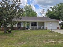 Charming single-story home featuring a cozy front porch, attached garage, and mature landscaping at 37 Oak Loop, Ocala, FL 34472