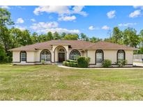 Charming single-story home featuring arched windows and a meticulously landscaped front yard at 4973 Sw 107Th Loop, Ocala, FL 34476