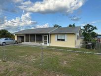 Charming single-story home with a screened porch and attached garage under a cloudy blue sky at 499 Water Rd, Ocala, FL 34472