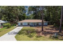 Charming light blue single-story home with well-manicured front yard and long driveway at 6475 Nw 61St Ave, Ocala, FL 34482