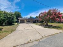 Charming single-story home featuring a lovely front yard with mature landscaping and a long driveway at 6814 Se 53Rd Pl, Ocala, FL 34472
