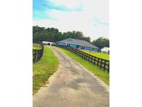 A long driveway leads to a single-story home with a black fenced in yard at 12524 Sw 109Th Pl, Dunnellon, FL 34432