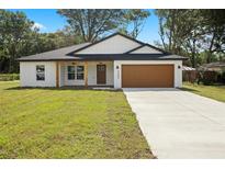 Charming single-story home featuring a well-manicured lawn, attached garage, and welcoming front porch at 13803 Se 44Th Ave, Summerfield, FL 34491