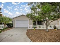 Charming one-story home featuring an attached garage, well-manicured landscaping, and a classic white picket fence at 1405 Espinoza Ln, The Villages, FL 32159