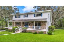 Charming two-story home featuring a brick facade, inviting front porch, and well-manicured lawn with mature trees at 510 Se 19Th St, Ocala, FL 34471