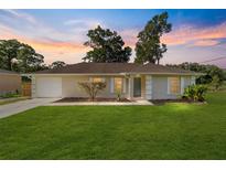 Charming single-story home with a well-manicured lawn, classic shutters, and a cozy, inviting facade at sunset at 5596 Nw 57Th St, Ocala, FL 34482