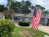Charming one-story home featuring well-manicured lawn, garden, and American flag at 8011 Sw 115Th Loop, Ocala, FL 34481