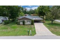 Charming single-story home featuring a spacious driveway and lush green lawn and mature trees at 5018 Se 106Th Pl, Belleview, FL 34420