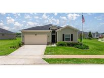 Charming single-story home featuring a two-car garage, well-manicured lawn, and an American flag at 7828 Sw 74Th Loop, Ocala, FL 34481